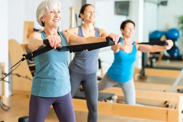 Toning Arms After 60: Empowering Womens Fitness Through Effective Weight Training 2 older woman doing weight training Wellingborough and resistance in the gym to tone upper arms